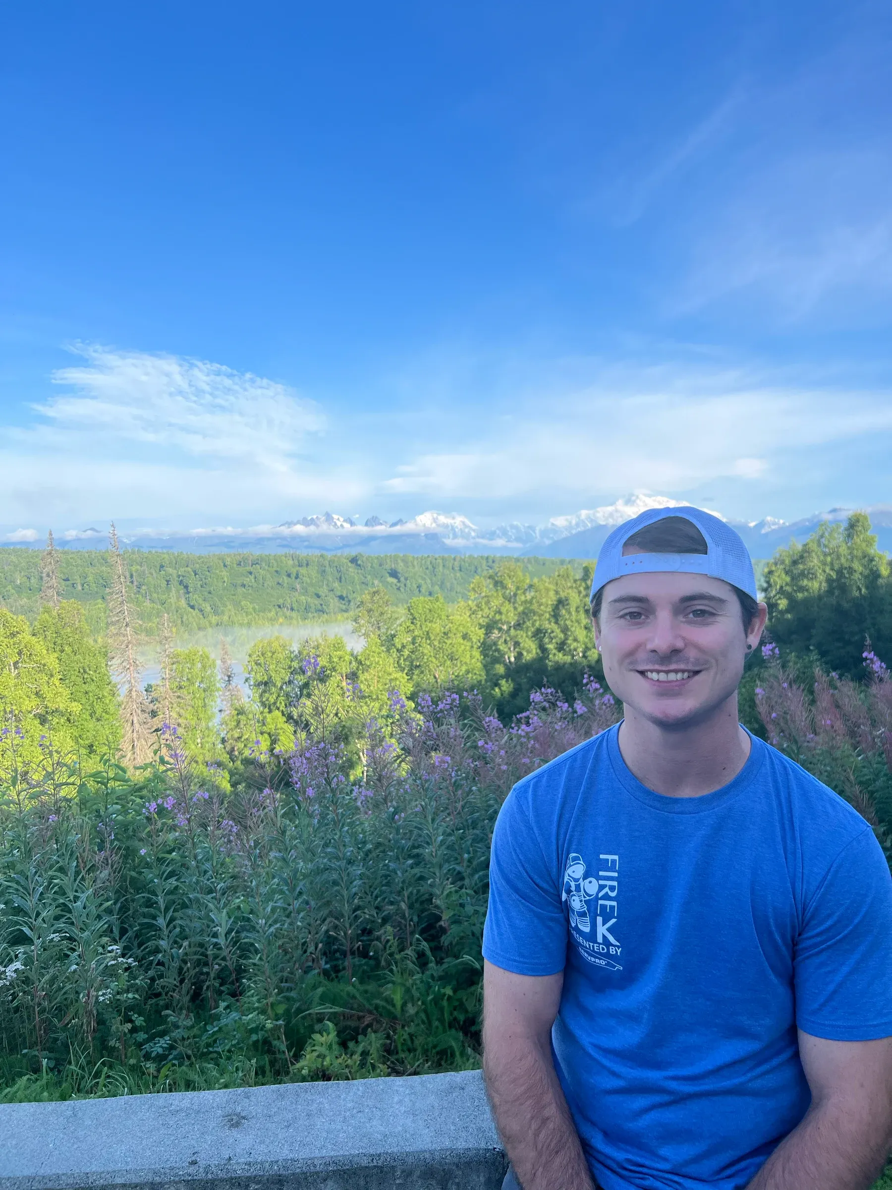 Dustin Snellings smiling outdoors in a blue cap and shirt